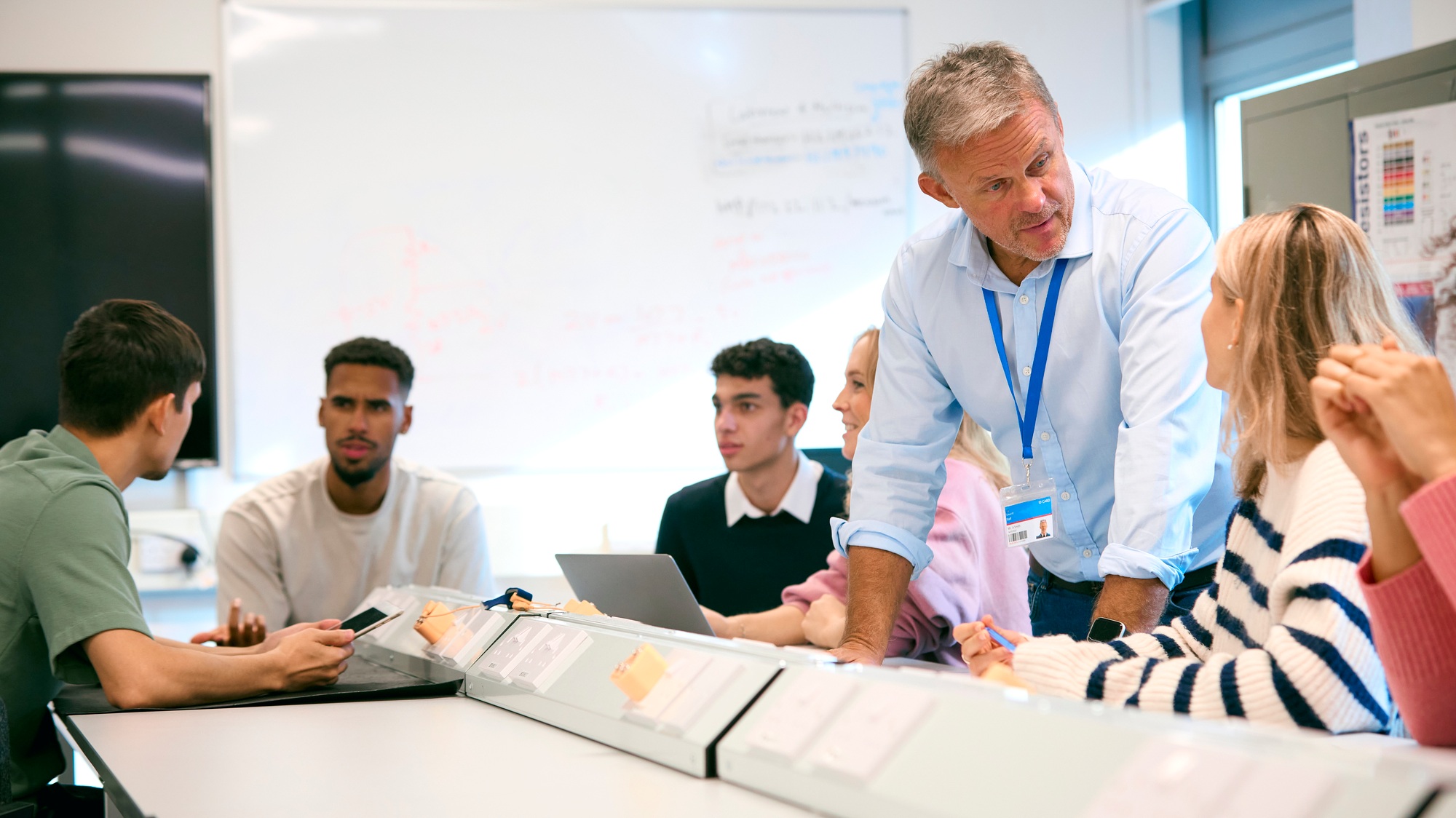 Male Tutor In Science Classroom Teaching Group Of College Or University Engineering Students